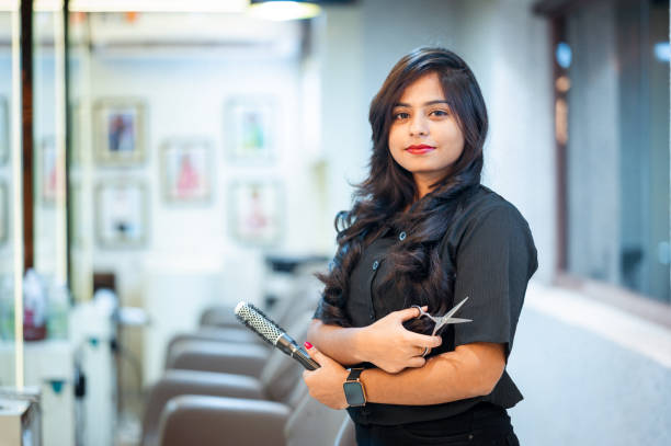 Portrait of young female hairdresser holding hair comb and scissor in salon Portrait of young female hairdresser holding hair comb and scissor in salon